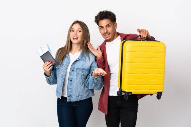 Mavi arka planda bir bavul tutan gezgin çift şaşırmış ve şok olmuş bir yüz ifadesine sahipler.