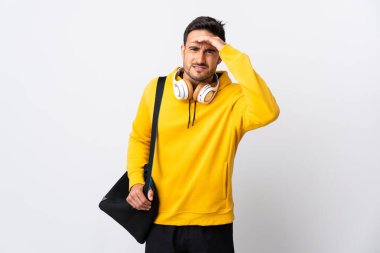 Spor çantalı genç bir adam beyaz arka planda izole edilmiş. Bir şeye bakmak için uzaklara bakıyor.