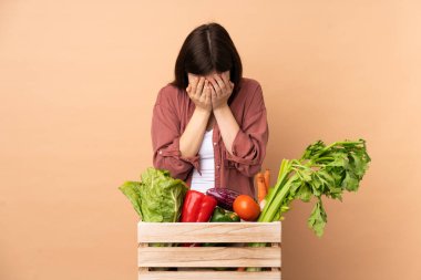 Taze sebze toplayan genç çiftçi kız yorgun ve hasta bir ifadeyle bir kutuda.