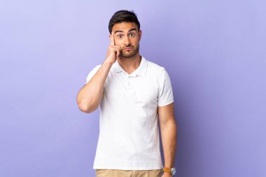 Mor arka planda izole edilmiş genç bir adam bir fikir düşünüyor.