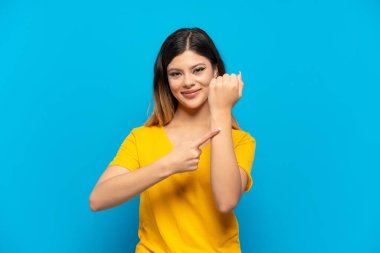 Genç Rus kız mavi arka planda izole edilmiş, geç kalma hareketi yapıyor.