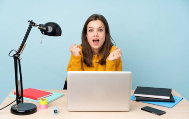 Evinde okuyan öğrenci kız mavi arka planda tek başına galibiyeti kutluyor.