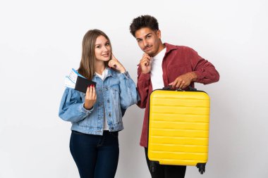 Mavi arka planda izole edilmiş bir bavul taşıyan gezgin çift tatlı bir ifadeyle gülümsüyor.