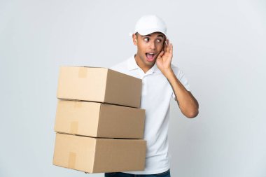 Teslimatçı Brezilyalı adam beyaz arka planda izole edilmiş bir şekilde elini kulağına koyarak bir şeyler dinliyor.