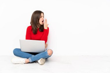 Polisle çalışan tenatif kız beyaz arka planda izole edilmiş esniyor ve geniş ağzını eliyle kapatıyor.