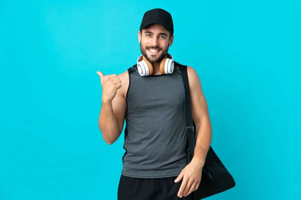 Jovem Desportista Com Saco Desportivo Isolado Sobre Fundo Azul Apontando — Fotografia de Stock