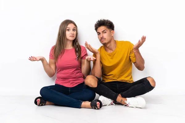 Young Couple Sitting Floor Isolated White Background Having Doubts While — Stock Photo, Image