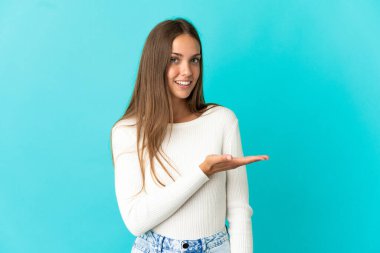 İzole edilmiş mavi arka planda genç bir kadın gülümseyerek bir fikir sunuyor.