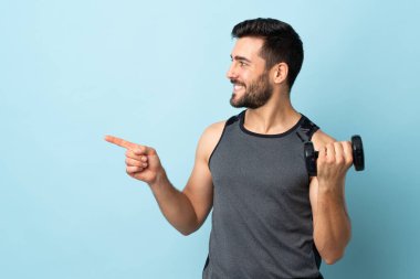 Sakallı, ağırlık kaldıran genç sporcu bir ürünü sunmak için kenarı işaret ediyor.