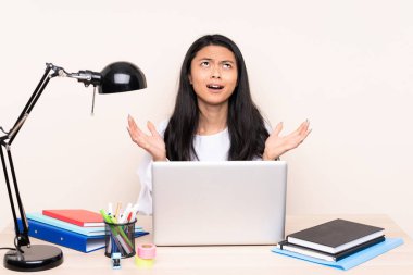 İş yerindeki Asyalı öğrenci bilgisayarlı bir kız bej arka planda izole edilmiş. Kötü bir durum yüzünden hayal kırıklığına uğramış.