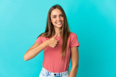 Soyutlanmış mavi arka planda genç bir kadın baş parmak işareti yapıyor.