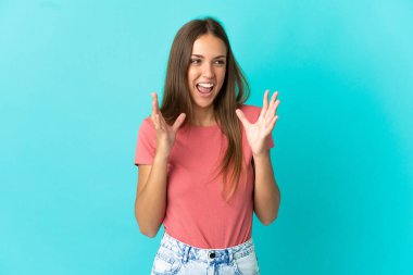 Soyutlanmış mavi arka planı olan genç bir kadın. Şaşırtıcı bir yüz ifadesi.