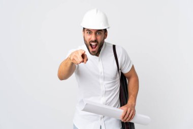 Miğferli ve elinde planları olan genç bir mimar beyaz arka planda izole edilmiş hayal kırıklığına uğramış ve ön tarafı işaret ediyor.