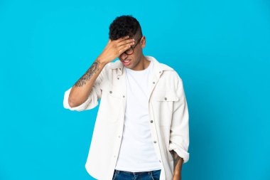 Mavi arka planda baş ağrısı olan genç Brezilyalı bir adam izole edilmiş.