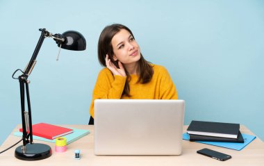 Öğrenci kız, mavi arka planda izole bir şekilde evinde ders çalışıyor.