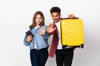 Mavi arka planda izole edilmiş bir bavul taşıyan gezgin çift yanlış bir şey düşündüğünü inkar etmeyi bırakıyorlar.