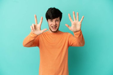 Mavi arka planda izole edilmiş genç Rus adam parmaklarıyla sekizi sayıyor