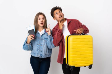 Gezgin çift mavi arka planda izole edilmiş bir bavul tutuyor.