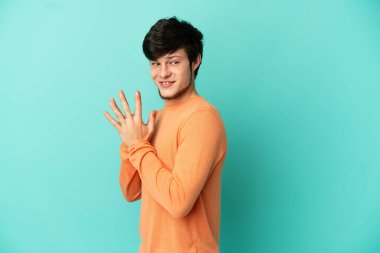 Genç Rus adam mavi arka planda bir şeyler çeviriyor.