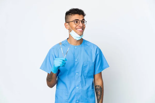 ブラジルの歯科医は白い背景に隔離されたツールを保持するアイデアを考えながら検索 — ストック写真