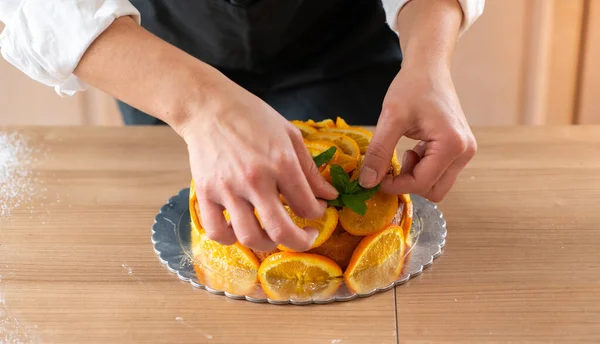 Młody Cukiernik Gotuje Ciasto Pomarańczowe Plasterkami Pomarańczy — Zdjęcie stockowe