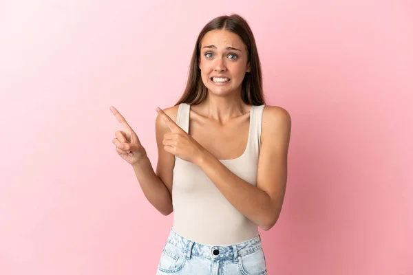 Jeune Femme Sur Fond Rose Isolé Effrayé Pointant Vers Côté — Photo