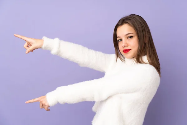 Tiener Meisje Geïsoleerd Paarse Achtergrond Wijzend Vinger Naar Zijkant Presenteren — Stockfoto