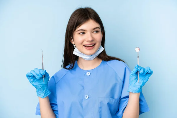 Młoda Dentystka Trzyma Narzędzia Odizolowanym Niebieskim Tle — Zdjęcie stockowe
