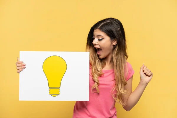 Young Russian Girl Isolated Yellow Background Holding Placard Bulb Icon — Stock Photo, Image