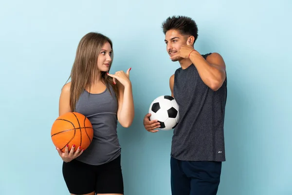 Young Couple Playing Football Basketball Isolated Blue Background Making Phone — Stock Photo, Image