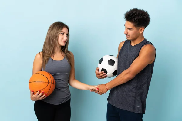 Jovem Casal Jogando Futebol Basquete Isolado Fundo Azul Handshaking Depois — Fotografia de Stock