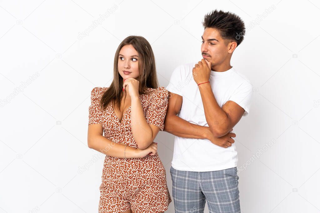 Young caucasian couple isolated on white background looking to the side