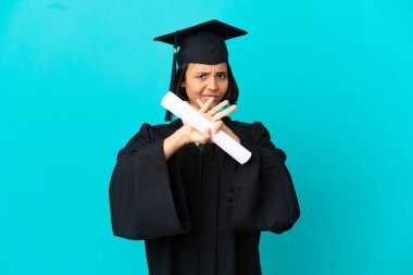 Üniversiteden mezun genç bir kız, izole edilmiş mavi arka planda bir davranışı durdurmak için el hareketi yapıyor.