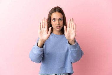 Soyutlanmış pembe arka planı olan genç bir kadın dur hareketi yapıyor ve hayal kırıklığına uğruyor.