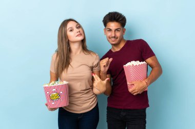 Çift, mor arka planda izole edilmiş bir film izlerken patlamış mısır yiyor gururlu ve kendini beğenmiş bir aşk konsepti.