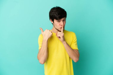 Mavi arka planda izole edilmiş genç bir Rus yan tarafı işaret ediyor ve sessiz hareketler yapıyor.