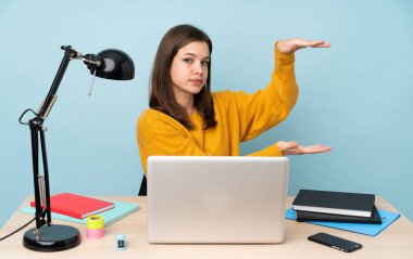 Öğrenci kız evinde çalışıyor. Mavi arka planda izole edilmiş. Kopyalama alanı var.