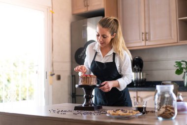 Genç pasta şefi mutfakta meyveli ev yapımı çikolatalı kek pişiriyor.