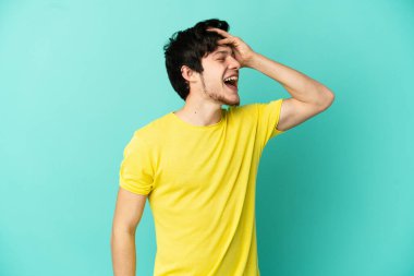 Genç Rus adam mavi arka planda izole edilmiş, gülümsüyor.