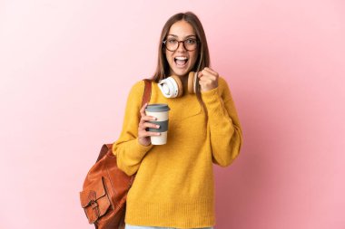 Soyutlanmış pembe arka planda genç bir bayan kazanan pozisyonu kutluyor.