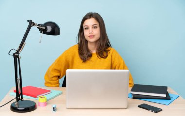 Öğrenci kız evinde çalışıyor. Arka planda mavi arka planda izole edilmiş.