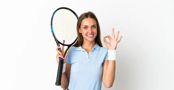 若いです女性上の隔離された白い背景プレイテニスと作るOkサイン — ストック写真