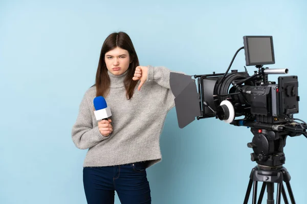 Młoda Reporterka Trzymająca Mikrofon Przekazująca Wiadomości Pokazujące Znak Opuszczenia Kciuka — Zdjęcie stockowe
