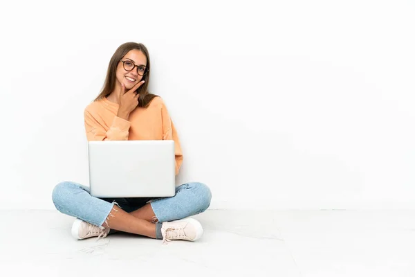 一个拿着笔记本电脑坐在地板上笑的年轻女人 — 图库照片