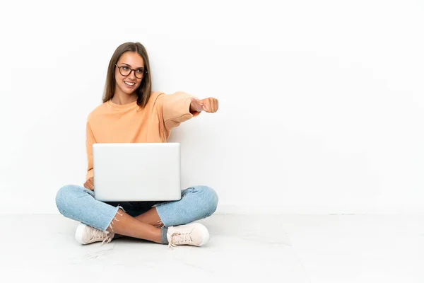 一个拿着笔记本电脑坐在地板上的年轻女人举起了一个大拇指 — 图库照片