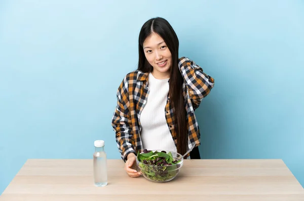 Young Chinese girl eating a salad laughing