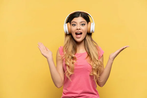 Joven Chica Rusa Aislada Sobre Fondo Amarillo Sorprendida Escuchando Música —  Fotos de Stock