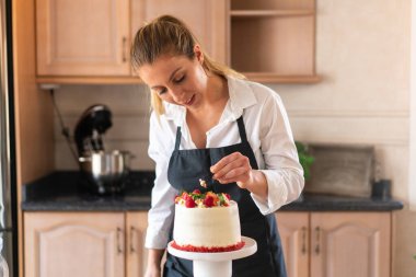 Genç pasta şefi mutfakta geleneksel kırmızı kadife kek pişiriyor.