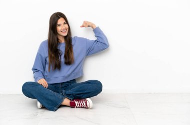 Yerde oturan genç bayan güçlü bir jest yapıyor.