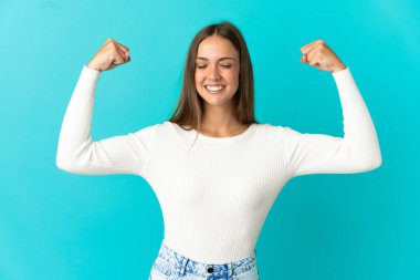 Soyutlanmış mavi arka planı olan genç bir kadın güçlü bir jest yapıyor.